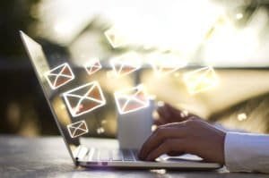 email marketing man on his laptop sending emails with little envelopes